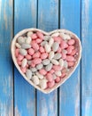 Colorful candy in white heart shaped bowl on wooden table Royalty Free Stock Photo