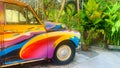A colorful car is parked in front of a green bush Royalty Free Stock Photo
