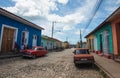 Colorful Caribbean aged village with cobblestone street, classic red car and Colonial house, Trinidad, Cuba, America. Royalty Free Stock Photo