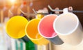 Colorful ceramic coffee cups hanging in a metal row with hook on wooden background at kitchen Royalty Free Stock Photo