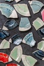 Colorful ceramic mosaic background, fragments and pieces of broken plates and bowls on the gray cement table