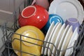 Colorful ceramic plates and bowls inside dishwasher basket getting washed Royalty Free Stock Photo