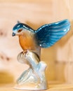 Colorful ceramic porcelain glazed bird landing on tree branch. Small Figurine on brown background. Spread your wings Royalty Free Stock Photo