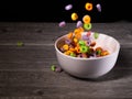 Colorful cereal rings falling into a white bowl on a gray table Royalty Free Stock Photo