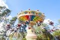 Colorful chain swing carousel in motion at amusement park on blue sky background.