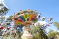 Colorful chain swing carousel in motion at amusement park on blue sky background.