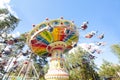 Colorful chain swing carousel in motion at amusement park on blue sky background.