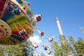 Colorful chain swing carousel in motion at amusement park on blue sky background.