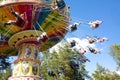 Colorful chain swing carousel in motion at amusement park on blue sky background.