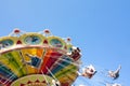 Colorful chain swing carousel in motion at amusement park on blue sky background.