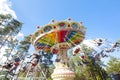 Colorful chain swing carousel in motion at amusement park on blue sky background.