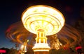 Colorful chain swing carousel in motion at amusement park at night.