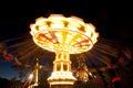 Colorful chain swing carousel in motion at amusement park at night.