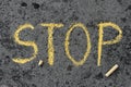 Chalk drawing: yellow word STOP and pieces of chalk