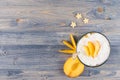 Colorful cheerful smoothie with yogurt, stars corn flakes ripe slice peach on blue wood board, top view.