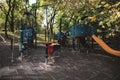 Colorful children`s playground with slides, swings and other objects in a public park with many trees around and no people Royalty Free Stock Photo