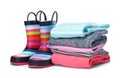 Colorful children`s rubber boots and stack of clothes Royalty Free Stock Photo