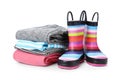 Colorful children`s rubber boots and stack of clothes Royalty Free Stock Photo