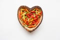 Colorful chili peppers in wooden dish heart shape.