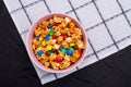 Colorful chocolate buttons and golden popcorn in bowl on napkin. Royalty Free Stock Photo