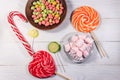 Colorful chocolate candies, lollipops, candy cane and marshmallows on wooden table