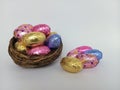 Colorful chocolate easter eggs overflowing a twig birds nest on a white background Royalty Free Stock Photo