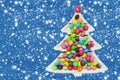 Colorful chocolates on a plate in the shape of a Christmas tree. Blue background with falling snow Royalty Free Stock Photo