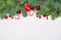 Colorful Christmas composition with green Xmas fir branch, red holly berries and baubles on white stucco plaster texture Royalty Free Stock Photo