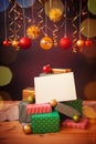 Colorful christmas gifts and balls with empty card for your text under red and golden Christmas decorations Royalty Free Stock Photo