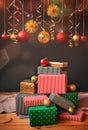 Colorful christmas gifts and balls under red and golden Christmas decorations and glowing lights hanging against dark background Royalty Free Stock Photo