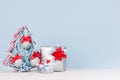 Colorful christmas home decoration - metallic gift boxes with bright red and blue silk ribbons and christmas tree on white wood. Royalty Free Stock Photo