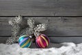 Colorful christmasballs on pile of snow against wooden wall Royalty Free Stock Photo