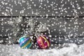 Colorful christmasballs on pile of snow against wooden wall Royalty Free Stock Photo