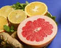 Colorful cirtus slices over blue background. Cut lemons and grapefruit with ginger on a plate Royalty Free Stock Photo