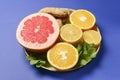 Colorful cirtus slices over blue background. Cut lemons and grapefruit with ginger on a plate Royalty Free Stock Photo