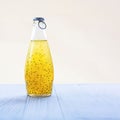 Colorful citrus refreshing summer drink with basil seeds in bottle with blue metal cap on light background. Square with