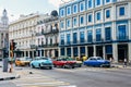 Colorful classic cars drive by old colorful buildings in Havana, Cuba. Royalty Free Stock Photo