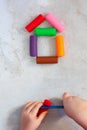 Colorful clay plasticine, modelling clay placed like house with child`s hands, vertical, education, child psychology,