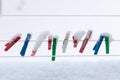 Colorful clips washing laundry covered snow strip rope outdoor. Winter.