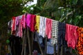 Colorful clothes hanging on rope in green garden. Multicolored textile clothing in asian village