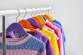 Colorful clothes hanging on wardrobe rack against light background Royalty Free Stock Photo