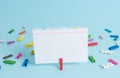 Colorful clothespin and rectangle square shaped colored paper in a blue background. Red clip hanging a note reminder in Royalty Free Stock Photo