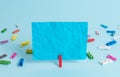Colorful clothespin and rectangle square shaped colored paper in a blue background. Red clip hanging a note reminder in Royalty Free Stock Photo