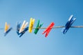Colorful clothespins on clothesline against blue sky