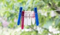 Colorful clothespins on a rope in the summer on the street. Multi-colored fabric clips on a white rope awaiting Royalty Free Stock Photo