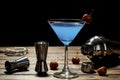 Colorful cocktail blue martini recipe with red cherry and bartender accessories on the wooden table in black background Royalty Free Stock Photo
