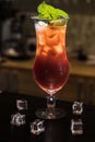 Colorful cocktail in glass on bar counter in pub or restaurant on bright blurred background. A lot of ice cubes and mint Royalty Free Stock Photo