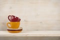 Colorful coffee cups on shelf over wooden background