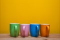 Colorful coffee cups on wooden table over yellow background Royalty Free Stock Photo