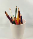 Colorful color pencils in a pink cup isolated Royalty Free Stock Photo